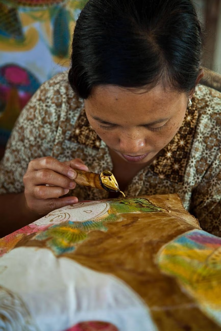 An Indonesian woman uses a tradition dyeing method for creating a batik print.