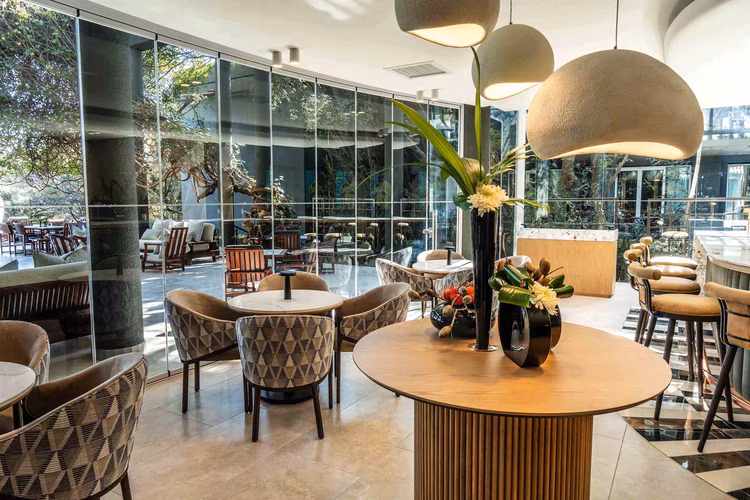 The Saxon Hotel’s elegant terrace basks in the afternoon light, where duck canapés and Pinotage set the stage for an unforgettable African-inspired tasting menu. (Image courtesy of Saxon Hotel, Villas, Spa).
